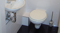 Gäste-WC kombiniert aus Wandfliesen mit Listellos als oberer Abschluss und Naturstein